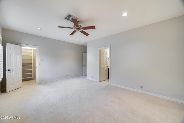 unfurnished bedroom with a spacious closet, light colored carpet, and ceiling fan