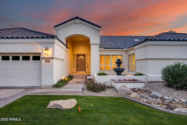 mediterranean / spanish-style house featuring a garage and a yard