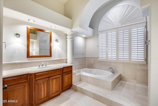 bathroom with ornate columns, vanity, tiled bath, and tile patterned floors