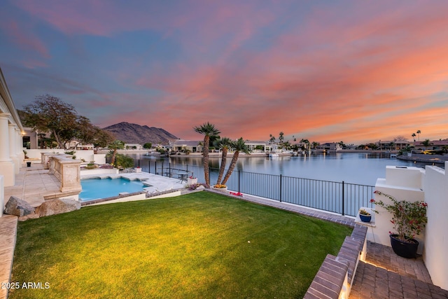 exterior space featuring a water and mountain view, a patio area, and a lawn