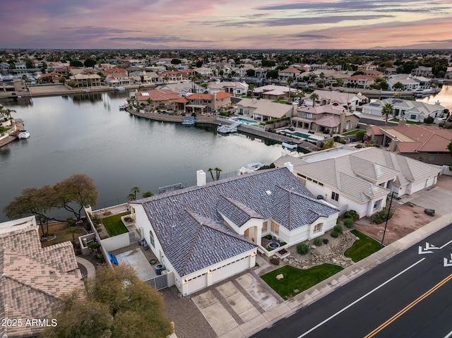 aerial view at dusk featuring a water view