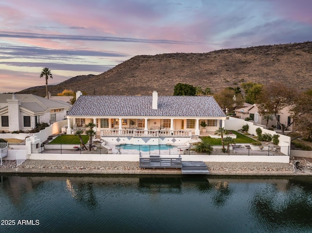 back house at dusk with a patio and a water and mountain view