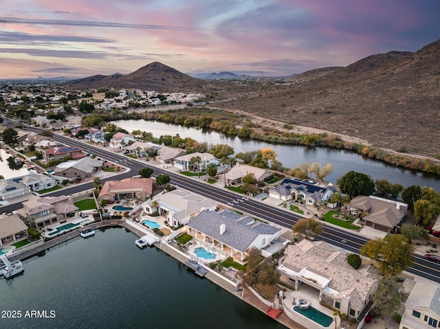 aerial view at dusk featuring a water and mountain view