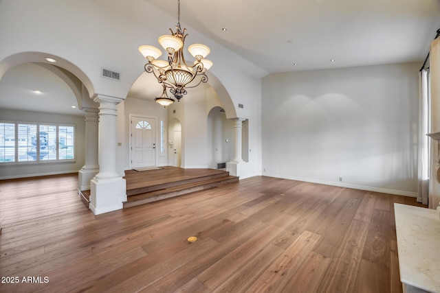 interior space with decorative columns, hardwood / wood-style floors, and high vaulted ceiling