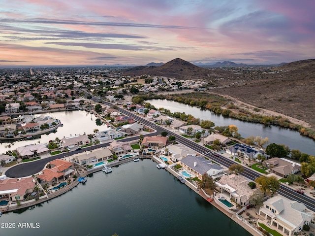 aerial view at dusk featuring a water and mountain view