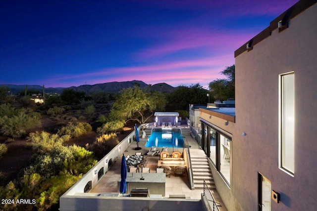 pool at dusk with a mountain view and a patio area