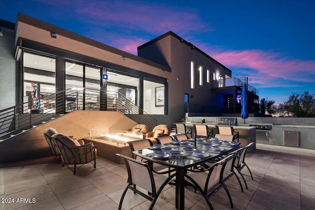 patio terrace at dusk with a balcony and area for grilling