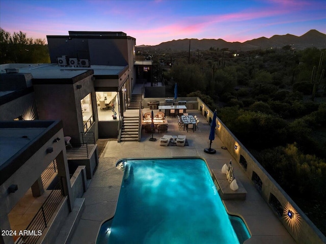 pool at dusk featuring a patio area and a mountain view