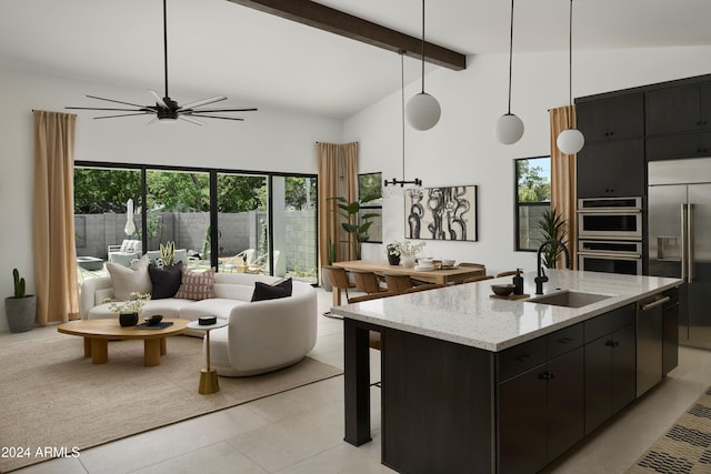 kitchen featuring appliances with stainless steel finishes, pendant lighting, sink, a kitchen island with sink, and beam ceiling