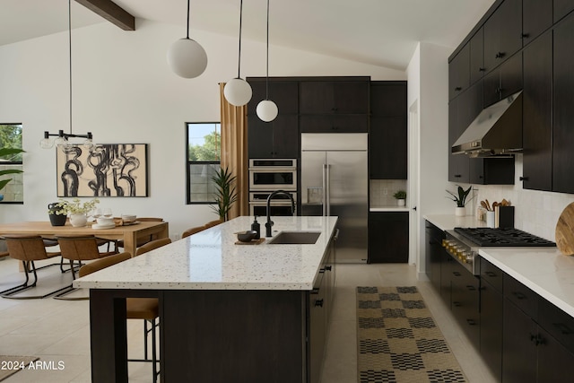 kitchen with sink, vaulted ceiling with beams, appliances with stainless steel finishes, an island with sink, and pendant lighting