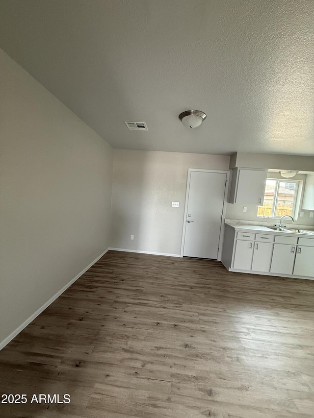 unfurnished dining area with sink, a textured ceiling, and light hardwood / wood-style floors