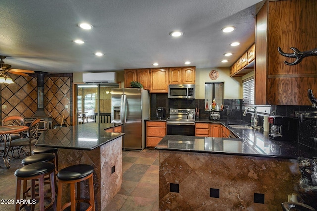 kitchen featuring a kitchen breakfast bar, backsplash, appliances with stainless steel finishes, sink, and ceiling fan