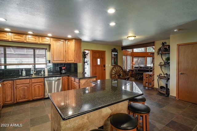 kitchen featuring a wealth of natural light, sink, dark tile flooring, and stainless steel dishwasher