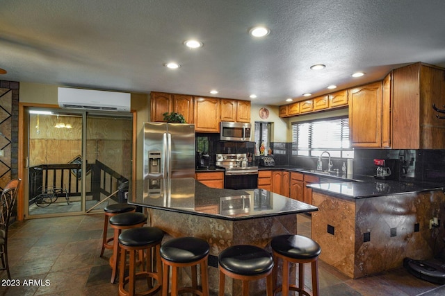 kitchen with stainless steel appliances, an AC wall unit, a kitchen breakfast bar, sink, and dark tile floors