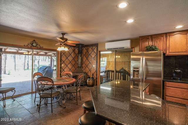 tiled dining area with a wall mounted air conditioner, ceiling fan, a textured ceiling, and a wood stove