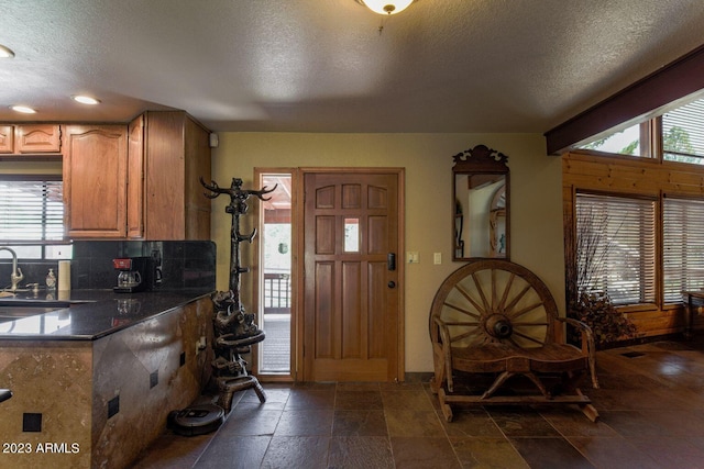 interior space featuring sink, dark tile flooring, and a textured ceiling