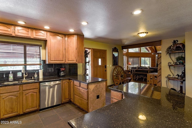 kitchen with kitchen peninsula, stainless steel dishwasher, a textured ceiling, dark stone countertops, and dark tile floors