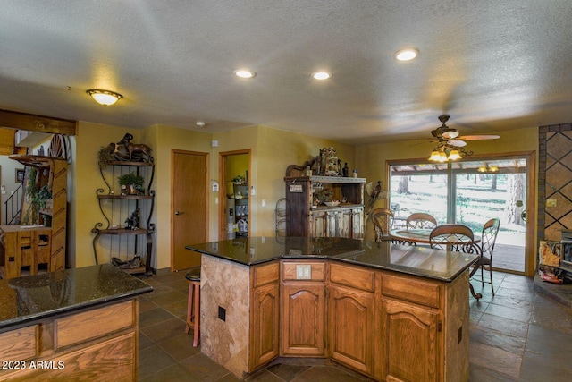 kitchen with a kitchen island, a textured ceiling, dark tile flooring, and ceiling fan