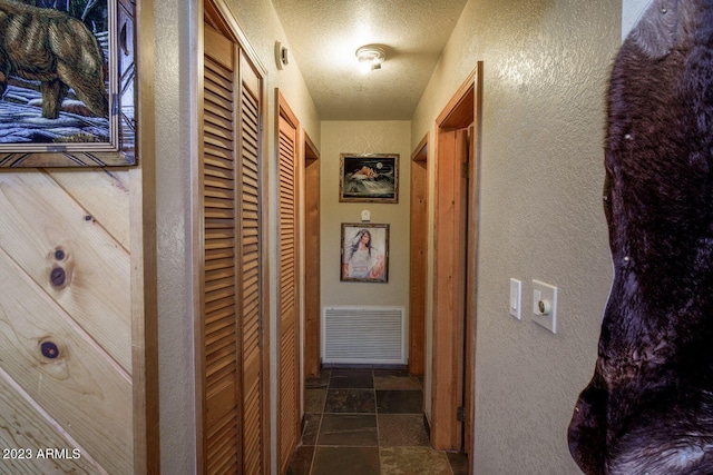 corridor featuring dark tile floors and a textured ceiling