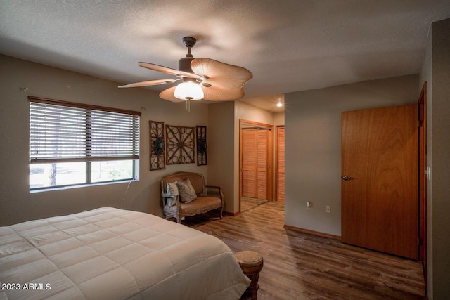 bedroom with wood-type flooring, a textured ceiling, ceiling fan, and a closet