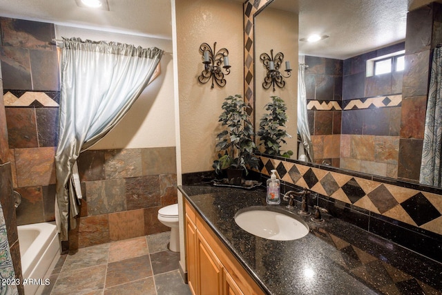 full bathroom featuring large vanity, shower / bath combo with shower curtain, a textured ceiling, tile floors, and toilet