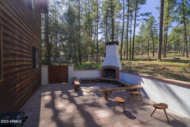 wooden deck with exterior fireplace and a patio area