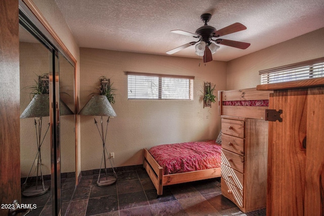 tiled bedroom featuring a closet, ceiling fan, and a textured ceiling