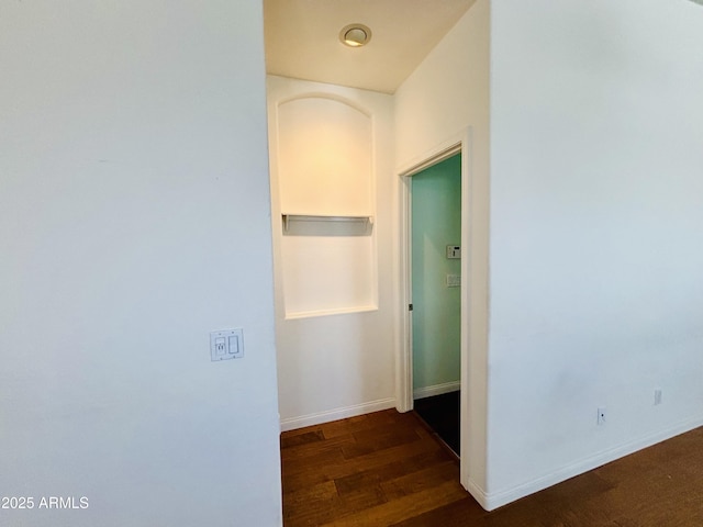 corridor featuring baseboards and dark wood finished floors