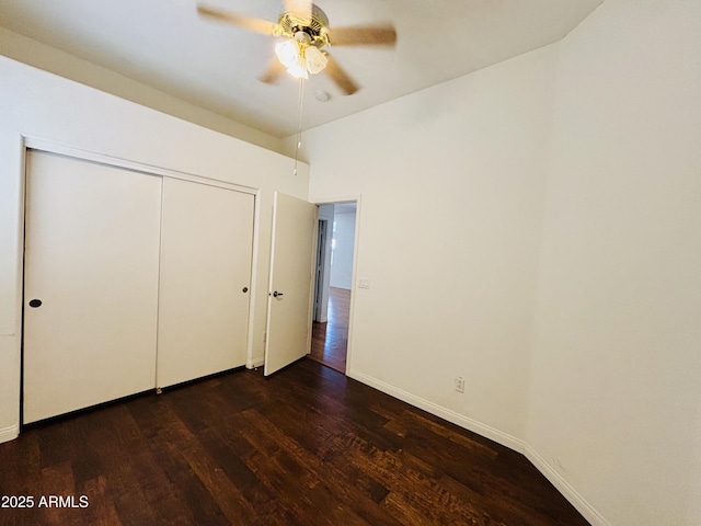 unfurnished bedroom featuring ceiling fan, a closet, baseboards, and dark wood finished floors