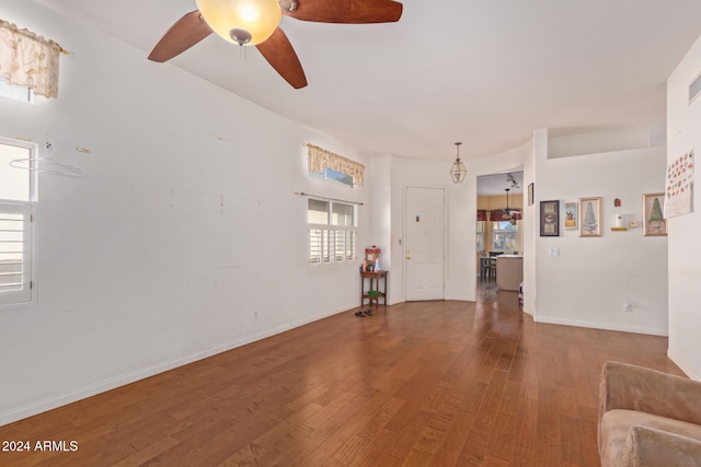 unfurnished living room featuring baseboards, wood finished floors, and a ceiling fan