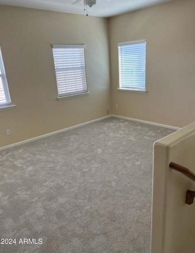 spare room featuring ceiling fan, carpet flooring, and a healthy amount of sunlight