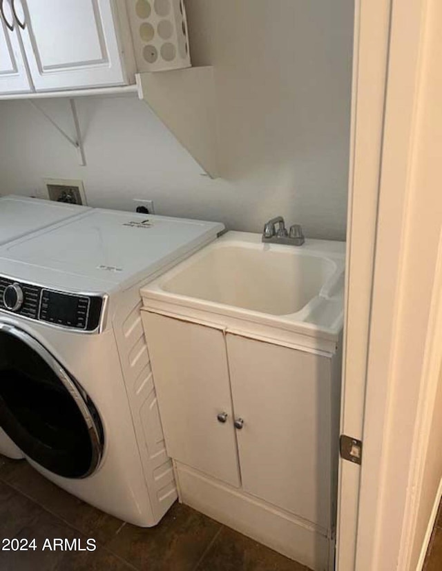 laundry room with washing machine and dryer, cabinets, dark tile patterned flooring, and sink