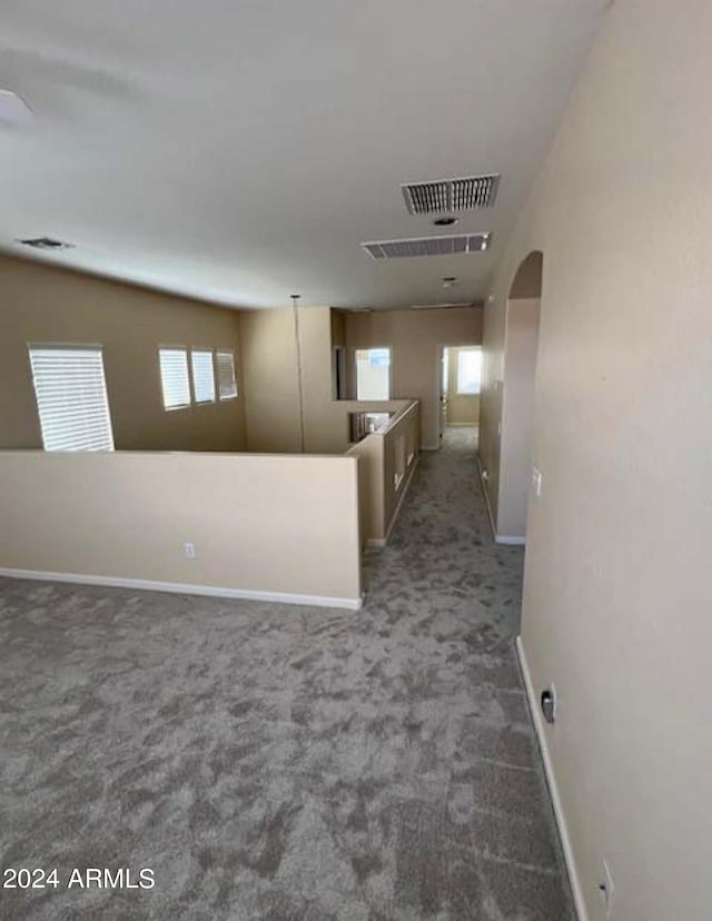 hallway with dark colored carpet, a wealth of natural light, and vaulted ceiling