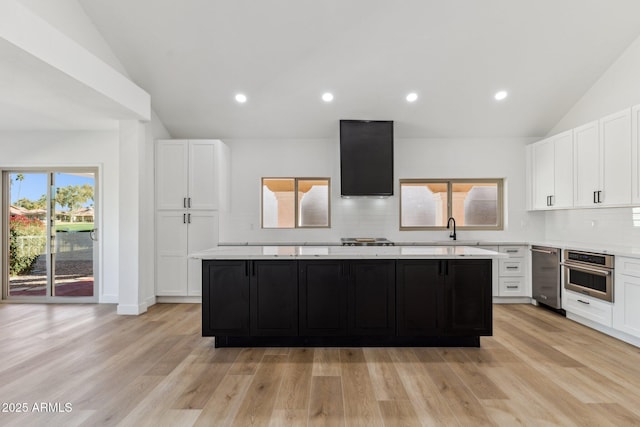 kitchen with light hardwood / wood-style flooring, white cabinetry, a kitchen island, and stainless steel oven