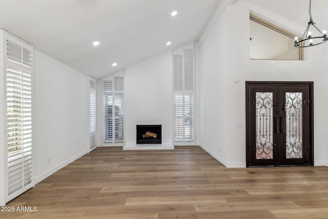 entrance foyer with a wealth of natural light, french doors, hardwood / wood-style floors, a chandelier, and lofted ceiling