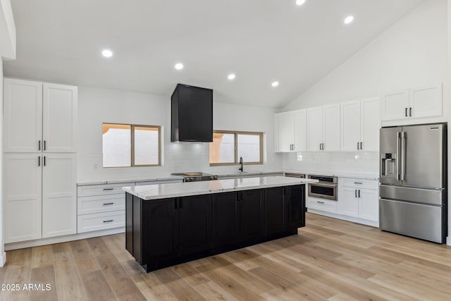 kitchen with appliances with stainless steel finishes, backsplash, light hardwood / wood-style flooring, white cabinets, and a center island