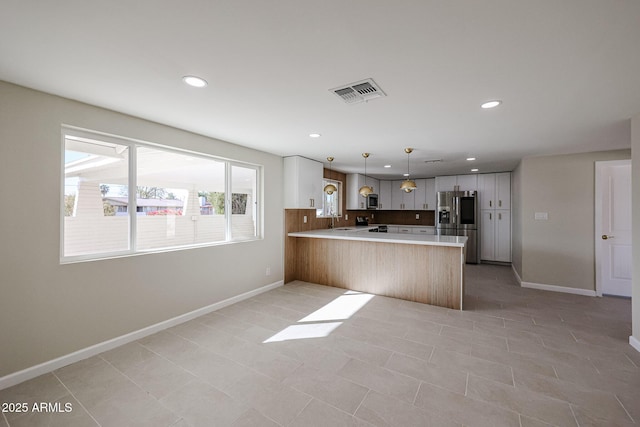 kitchen with sink, white cabinetry, appliances with stainless steel finishes, kitchen peninsula, and pendant lighting