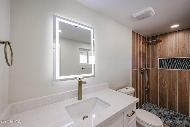 bathroom featuring vanity, a tile shower, and toilet