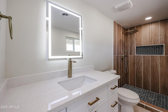 bathroom with vanity, a tile shower, and toilet