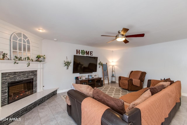 living room featuring ceiling fan and a stone fireplace