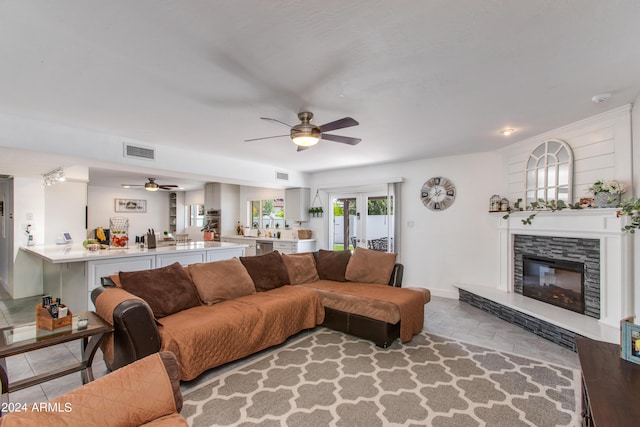 living room featuring ceiling fan and a stone fireplace