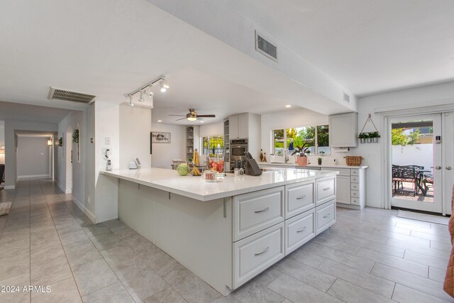 kitchen with ceiling fan, plenty of natural light, white cabinetry, and a breakfast bar