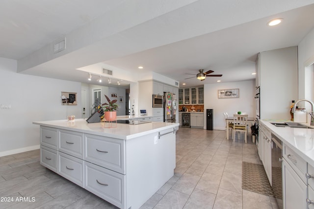 kitchen with ceiling fan, sink, a large island, stainless steel appliances, and white cabinets