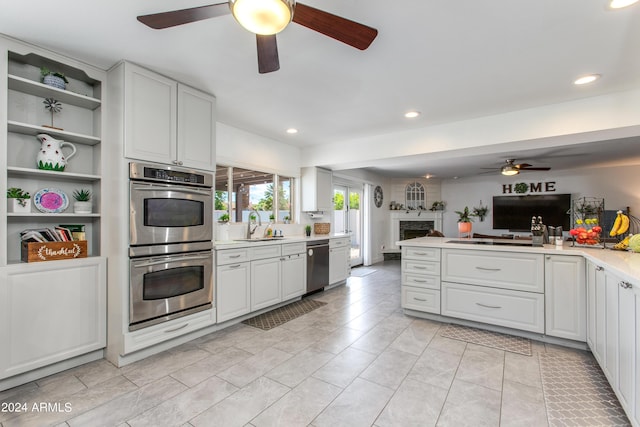 kitchen with kitchen peninsula, appliances with stainless steel finishes, ceiling fan, sink, and white cabinets