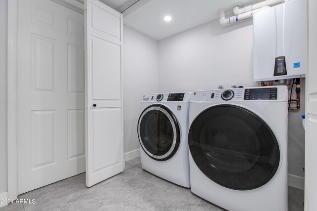 clothes washing area with light tile patterned floors, tankless water heater, and washer and clothes dryer