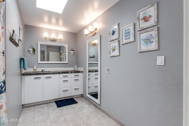 bathroom with tile patterned floors, a skylight, and vanity