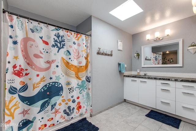 bathroom with tile patterned floors, vanity, a shower with shower curtain, and a skylight