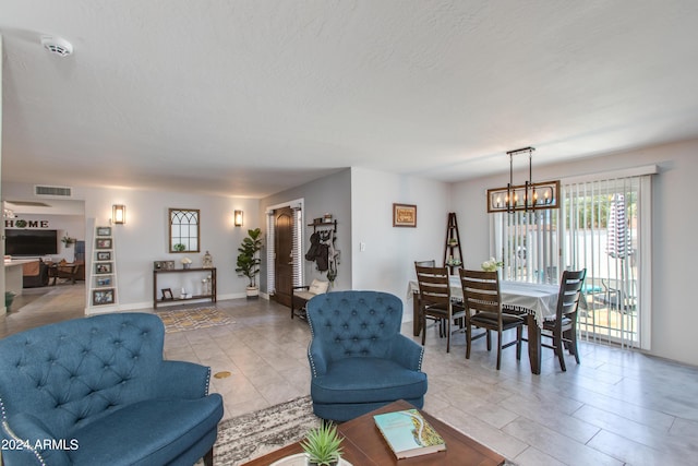 living room with light tile patterned flooring, a textured ceiling, and a notable chandelier