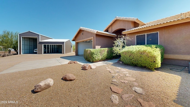 view of front facade featuring a tile roof, driveway, and stucco siding