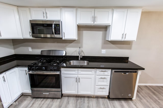 kitchen with white cabinetry, sink, light hardwood / wood-style floors, and appliances with stainless steel finishes